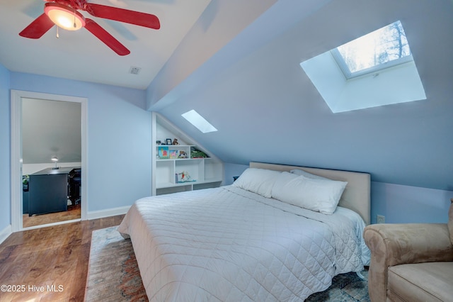 bedroom featuring wood-type flooring, lofted ceiling with skylight, and ceiling fan