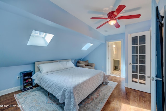 bedroom featuring dark hardwood / wood-style flooring, lofted ceiling with skylight, and ceiling fan