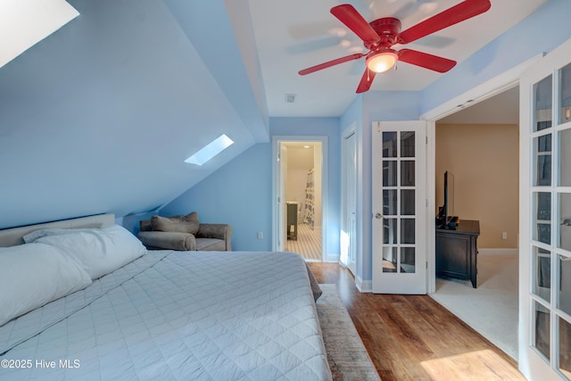 bedroom with wood-type flooring, vaulted ceiling with skylight, and french doors