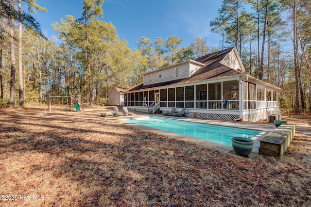 back of property with a playground, a sunroom, and central AC unit