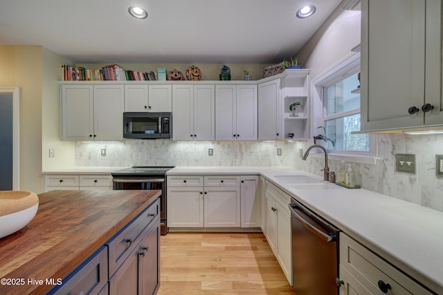 kitchen with white cabinetry, butcher block countertops, sink, and appliances with stainless steel finishes