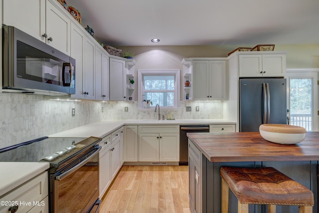 kitchen featuring wood counters, stainless steel appliances, sink, and white cabinets