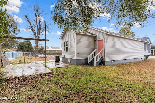 rear view of house with cooling unit, a patio area, and a lawn