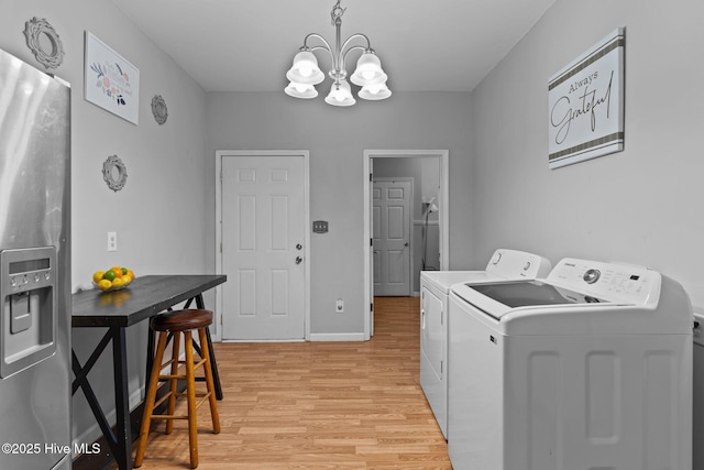 laundry area featuring a chandelier, light hardwood / wood-style floors, and washer and dryer