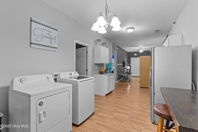 clothes washing area with washing machine and dryer, ceiling fan with notable chandelier, and light wood-type flooring