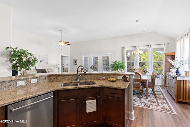 kitchen featuring vaulted ceiling, hardwood / wood-style floors, sink, stainless steel dishwasher, and light stone countertops