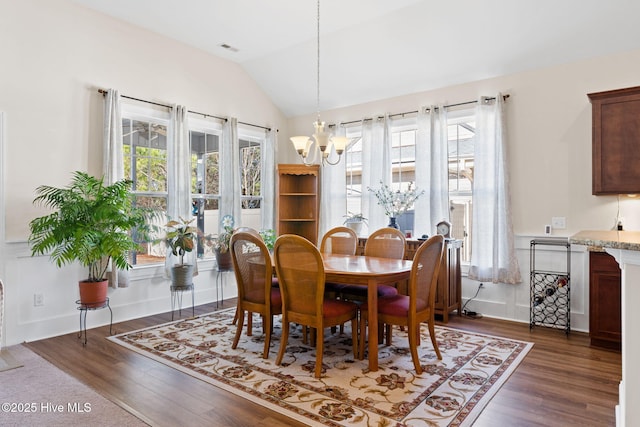 dining area with an inviting chandelier, lofted ceiling, and dark hardwood / wood-style floors