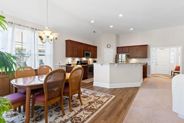 dining space featuring dark hardwood / wood-style floors, vaulted ceiling, and a notable chandelier