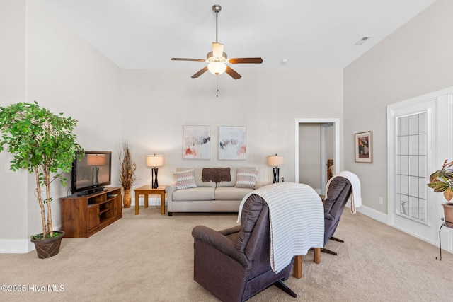 carpeted living room with ceiling fan and a high ceiling