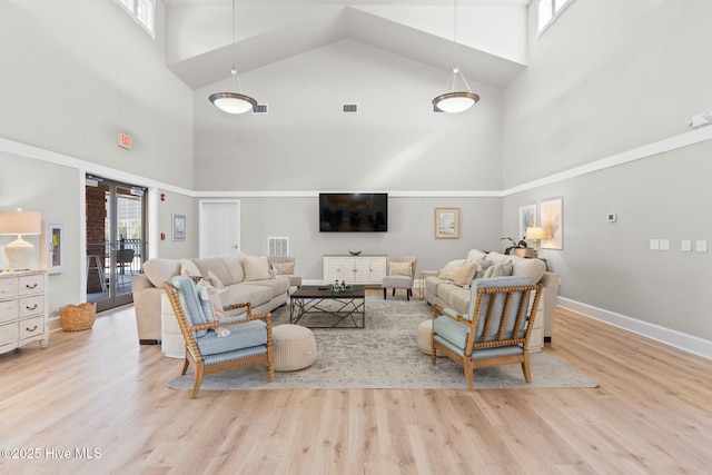 living room featuring a towering ceiling, french doors, and light wood-type flooring