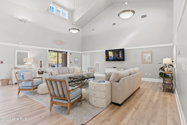 living room with a towering ceiling, a wealth of natural light, and light wood-type flooring