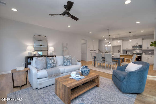 living area with light wood-style flooring, baseboards, a ceiling fan, and recessed lighting