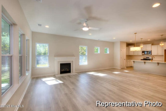 unfurnished living room featuring ceiling fan and light hardwood / wood-style floors