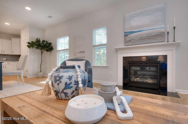 interior space with a glass covered fireplace, baseboards, and recessed lighting