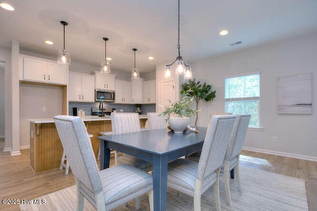 dining room featuring light wood finished floors, recessed lighting, and baseboards