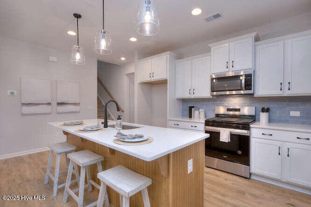 kitchen with light countertops, appliances with stainless steel finishes, backsplash, and a sink