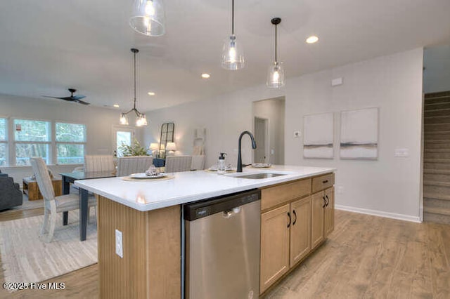 kitchen with a kitchen island with sink, a sink, light wood-style floors, light countertops, and dishwasher