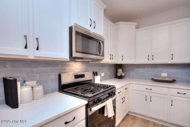 kitchen featuring stainless steel appliances, backsplash, light countertops, and white cabinetry