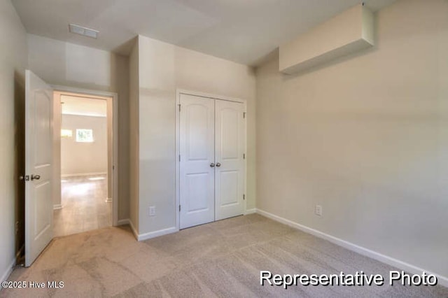 unfurnished bedroom featuring light colored carpet and a closet