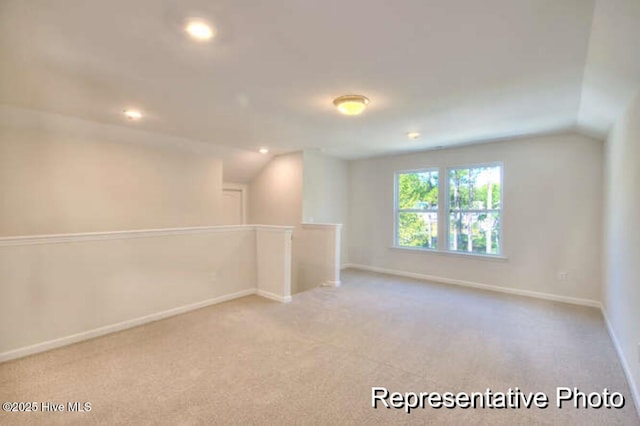 spare room featuring vaulted ceiling and light colored carpet