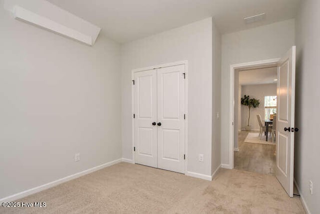 bedroom with a closet, light colored carpet, and baseboards