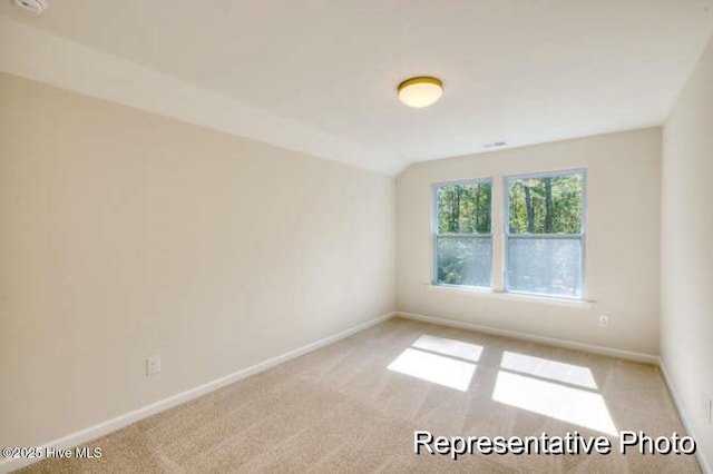 carpeted empty room with lofted ceiling