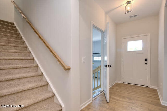 foyer entrance with stairs, wood finished floors, visible vents, and baseboards