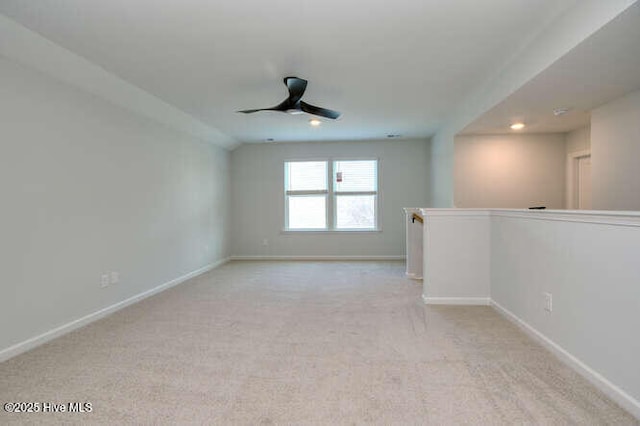 spare room featuring light carpet, ceiling fan, and baseboards