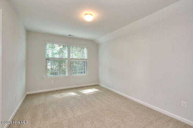 empty room featuring carpet floors, baseboards, and lofted ceiling