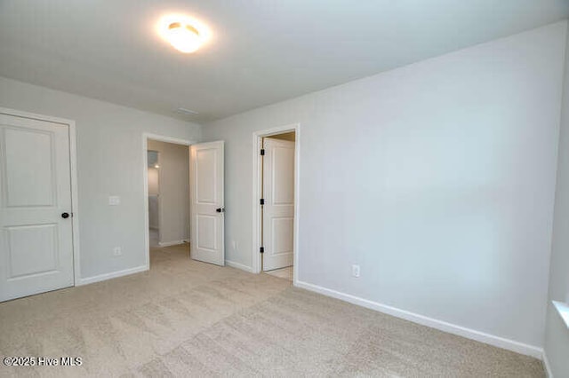 unfurnished bedroom with light carpet and baseboards