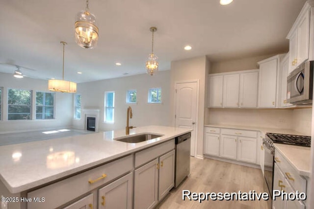 kitchen with sink, decorative light fixtures, an island with sink, and appliances with stainless steel finishes