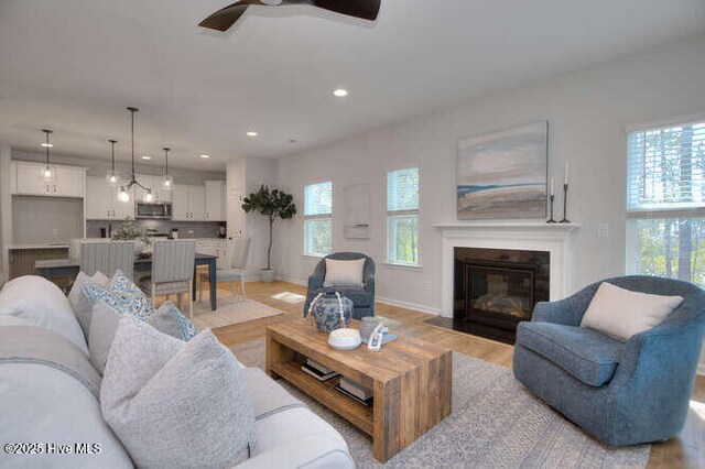 kitchen featuring decorative light fixtures, appliances with stainless steel finishes, an island with sink, light hardwood / wood-style floors, and white cabinets