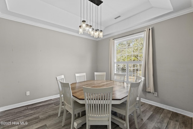 dining area with dark hardwood / wood-style flooring, a tray ceiling, and crown molding