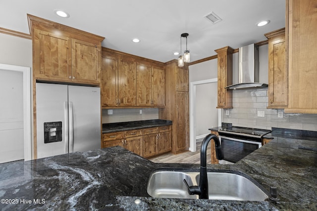 kitchen with sink, wall chimney range hood, electric range oven, hanging light fixtures, and stainless steel fridge with ice dispenser