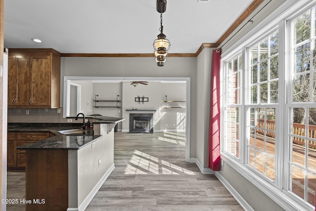 kitchen with sink, decorative light fixtures, plenty of natural light, dark stone counters, and backsplash