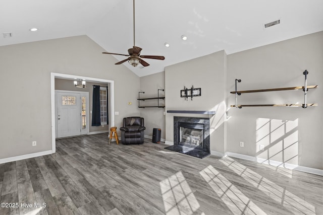 unfurnished living room with hardwood / wood-style flooring, a high end fireplace, high vaulted ceiling, and ceiling fan