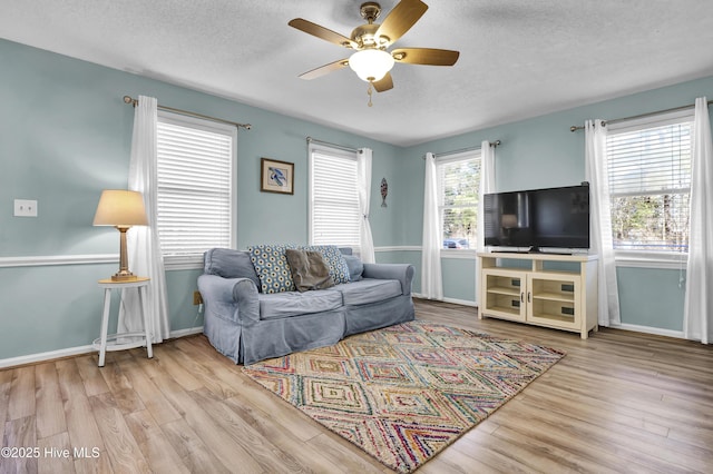 living room featuring ceiling fan, a textured ceiling, and light wood-type flooring