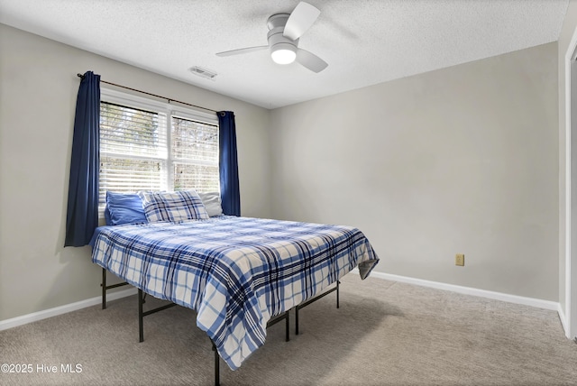 carpeted bedroom featuring ceiling fan and a textured ceiling