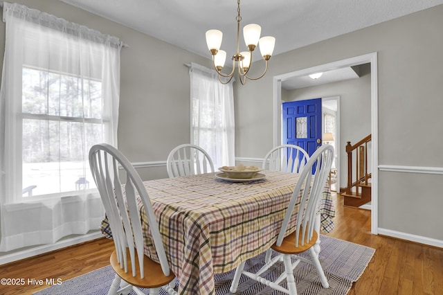 dining area with wood-type flooring and a chandelier