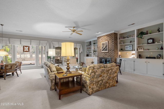 carpeted living room with crown molding, a textured ceiling, built in features, ceiling fan, and a fireplace