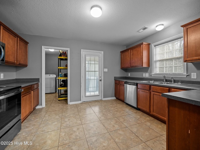 kitchen with light tile patterned floors, sink, appliances with stainless steel finishes, a textured ceiling, and washer / clothes dryer