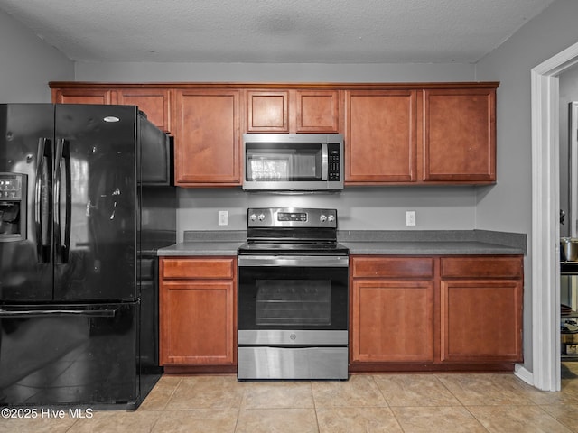 kitchen featuring stainless steel appliances, light tile patterned floors, and a textured ceiling