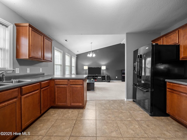 kitchen featuring sink, vaulted ceiling, black refrigerator with ice dispenser, a notable chandelier, and pendant lighting