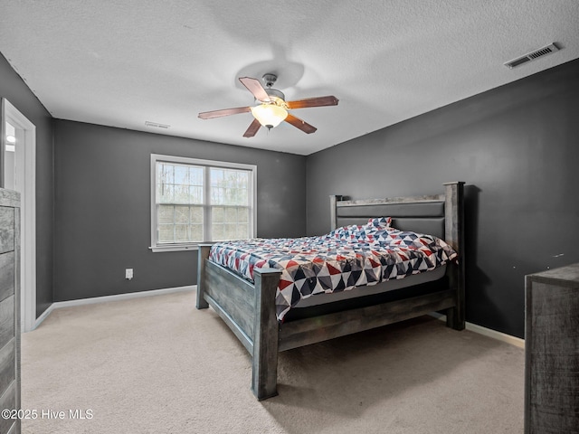 bedroom with ceiling fan, light colored carpet, and a textured ceiling