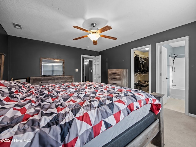 carpeted bedroom with ceiling fan, ensuite bathroom, a textured ceiling, a spacious closet, and a closet