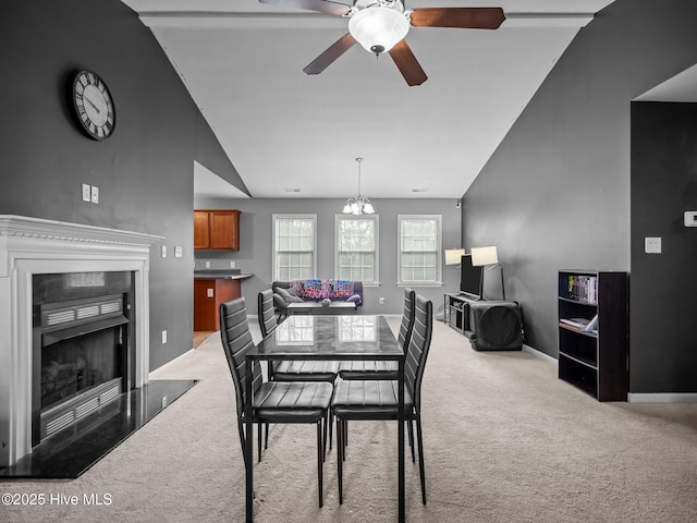 dining area featuring vaulted ceiling, ceiling fan with notable chandelier, and light colored carpet