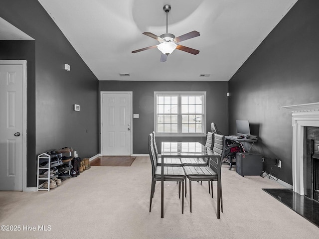 carpeted dining room with lofted ceiling, a fireplace, and ceiling fan