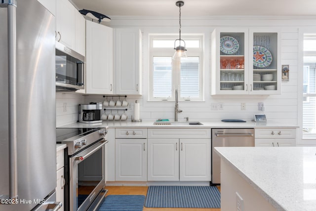 kitchen featuring sink, white cabinetry, hanging light fixtures, appliances with stainless steel finishes, and a wealth of natural light