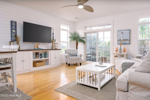 living room with crown molding, ceiling fan, and light hardwood / wood-style floors