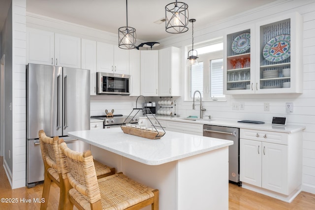 kitchen with sink, appliances with stainless steel finishes, a kitchen breakfast bar, a kitchen island, and decorative light fixtures